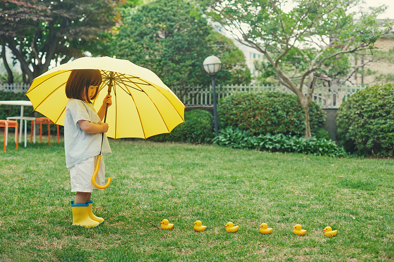 一个孩子举着一把黄色的伞图片素材