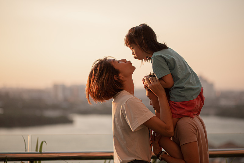 一个亚洲华人家庭和一个孩子在户外欣赏春天的日落美景。图片素材