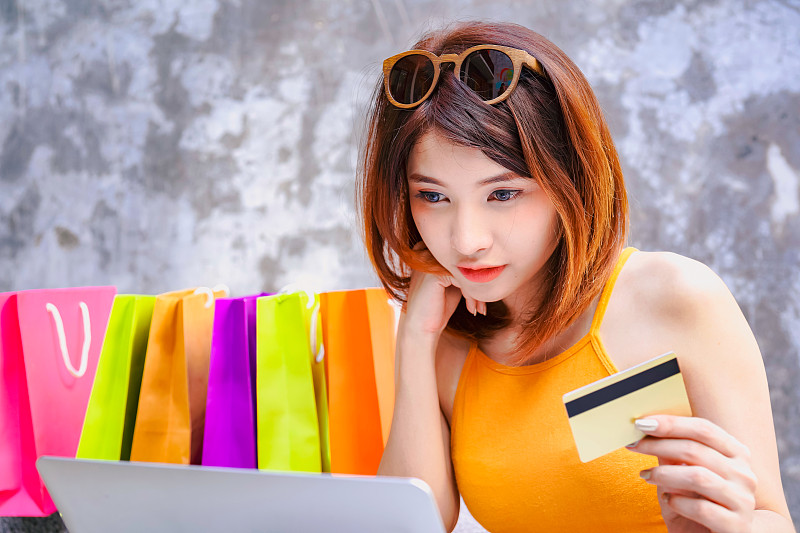 快乐购物者亚洲妇女持有信用卡网上购物图片下载