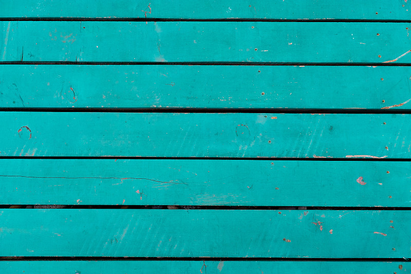 有绳结的旧蓝色或青绿色木板木质结构，有质感的彩绘背景。一面油漆褪色剥落的旧横幅。码头上明亮的木制平台或甲板摄影图片