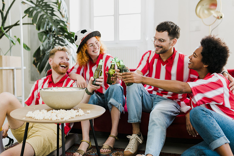 一群欢呼的人吃着爆米花，喝着啤酒，看电视上的足球比赛，在他们的球队进球后庆祝胜利图片下载
