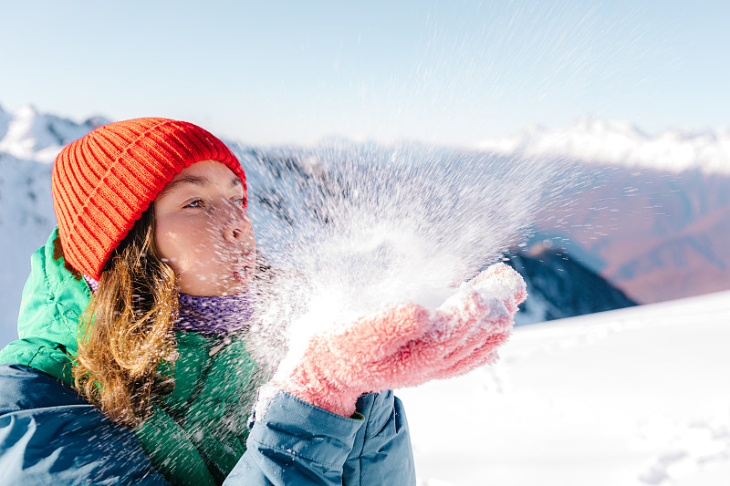 女人玩得很开心，在雪上吹气图片下载