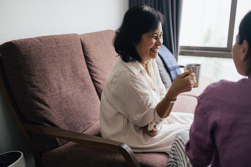 一位快乐美丽的老年妇女一边喝茶一边和她的女儿说话图片下载