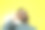 一名戴着墨镜的男子站在黄色的墙前摄影图片