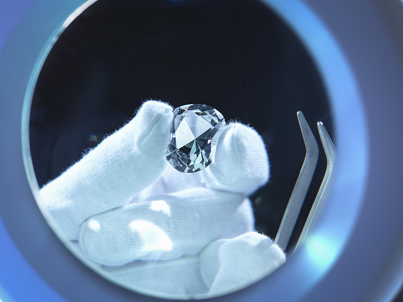 Jeweller inspecting replica diamonds with gloved hand图片素材