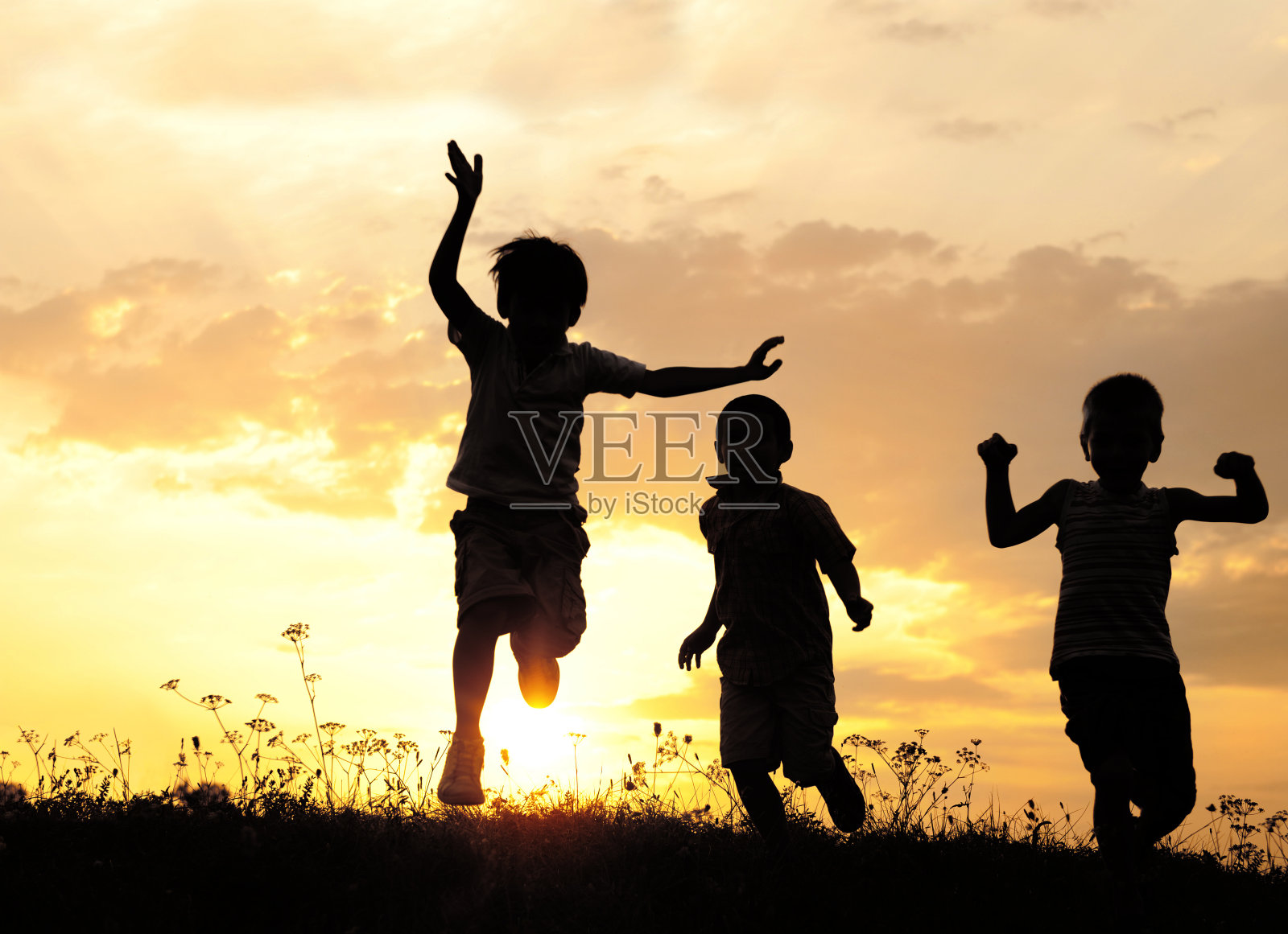 日落时分，孩子们在草地上奔跑照片摄影图片