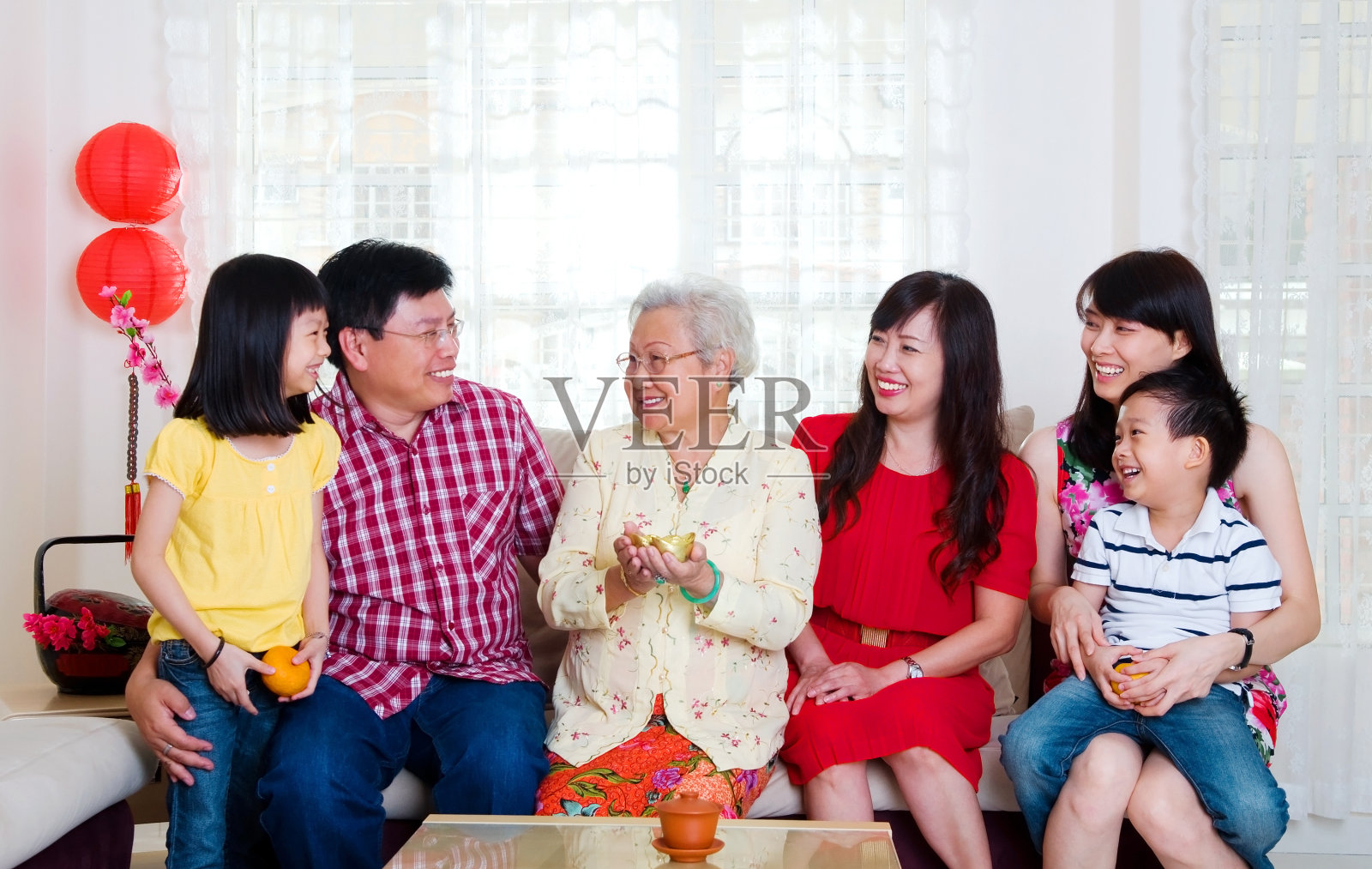 一家人微笑着坐在沙发上庆祝春节照片摄影图片
