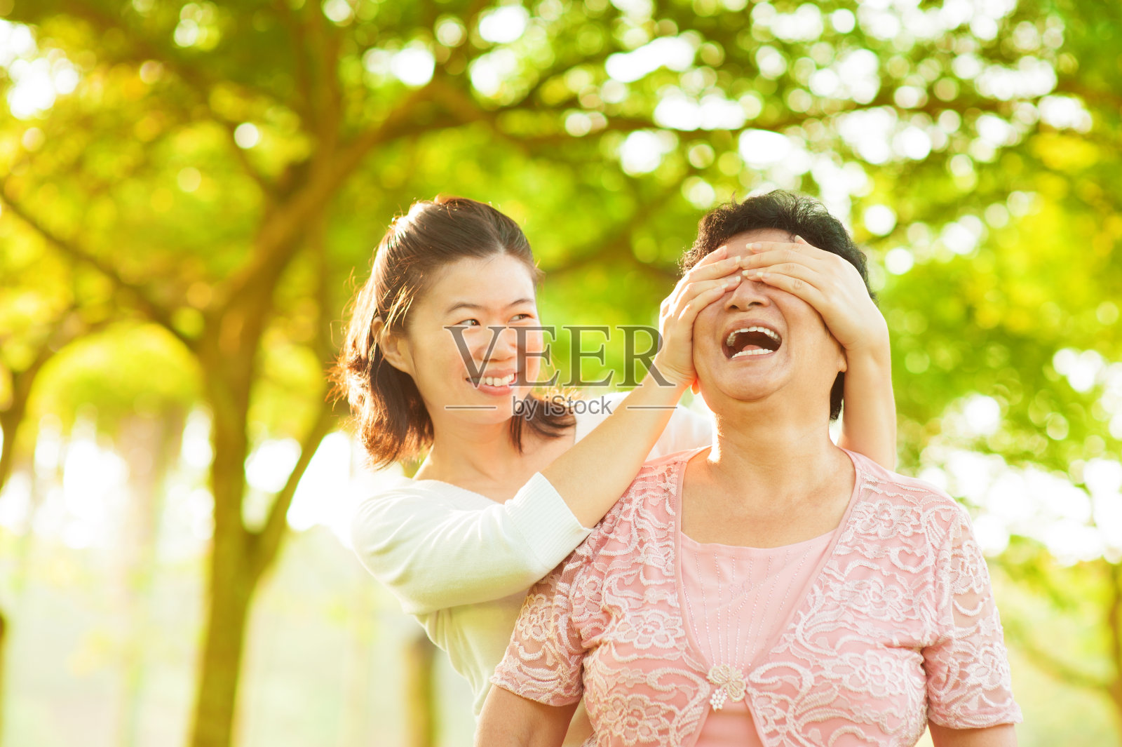 一位微笑的年轻女子遮住了一位年长女子的眼睛照片摄影图片