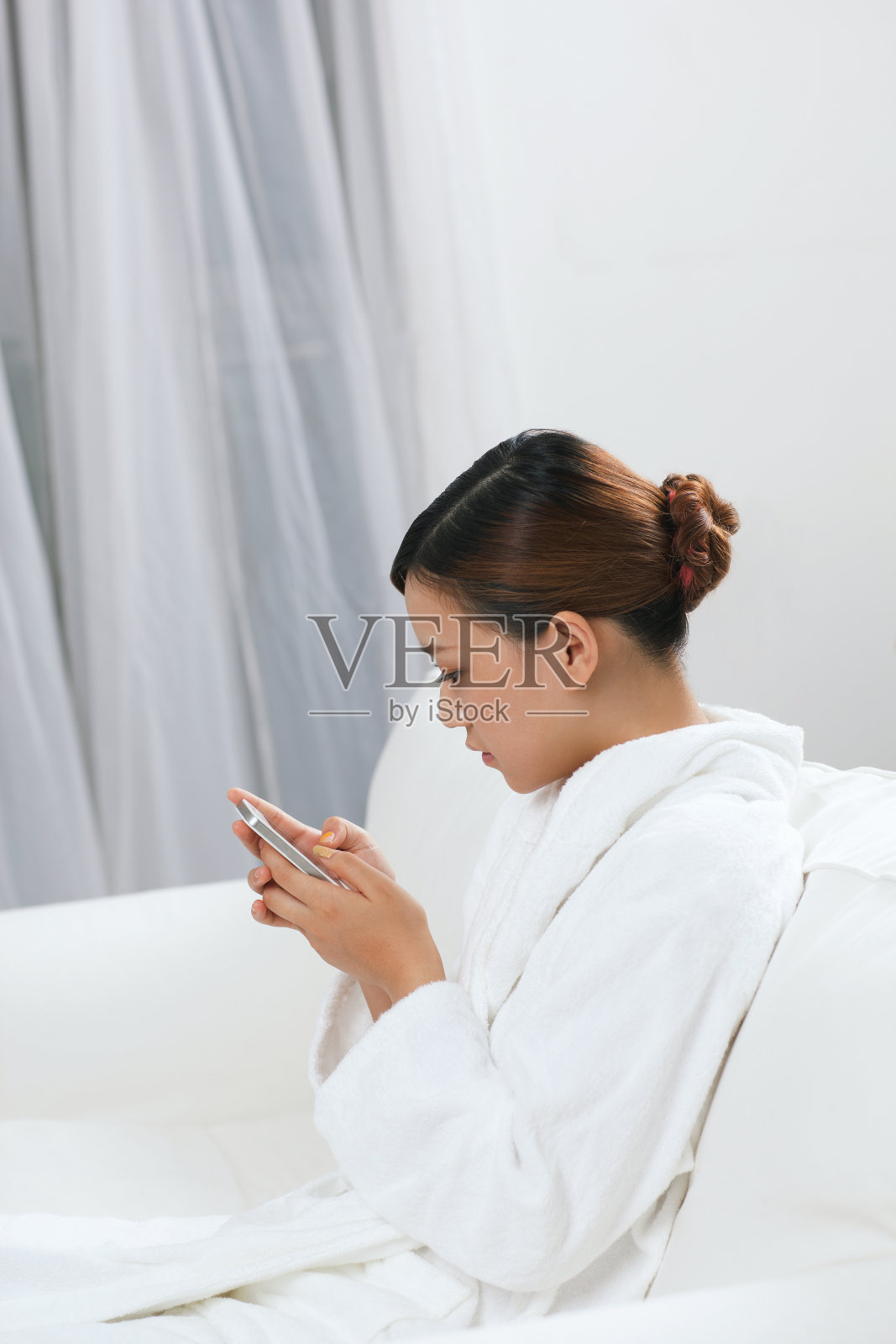 年轻女子穿着浴袍坐在沙发上发短信照片摄影图片