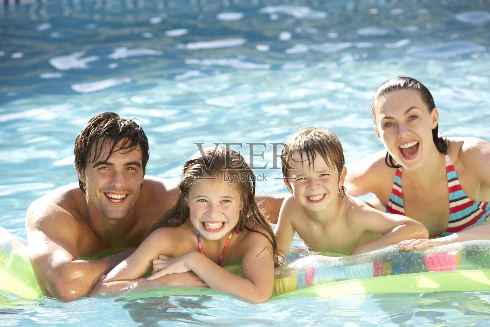 年轻的家庭在游泳池里放松照片摄影图片