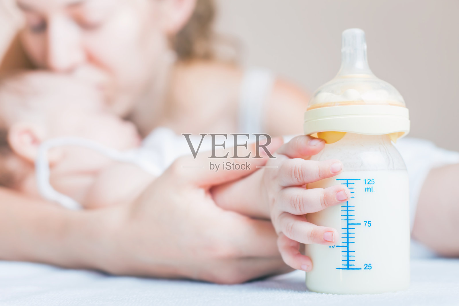 婴儿抱着装着母乳的奶瓶照片摄影图片
