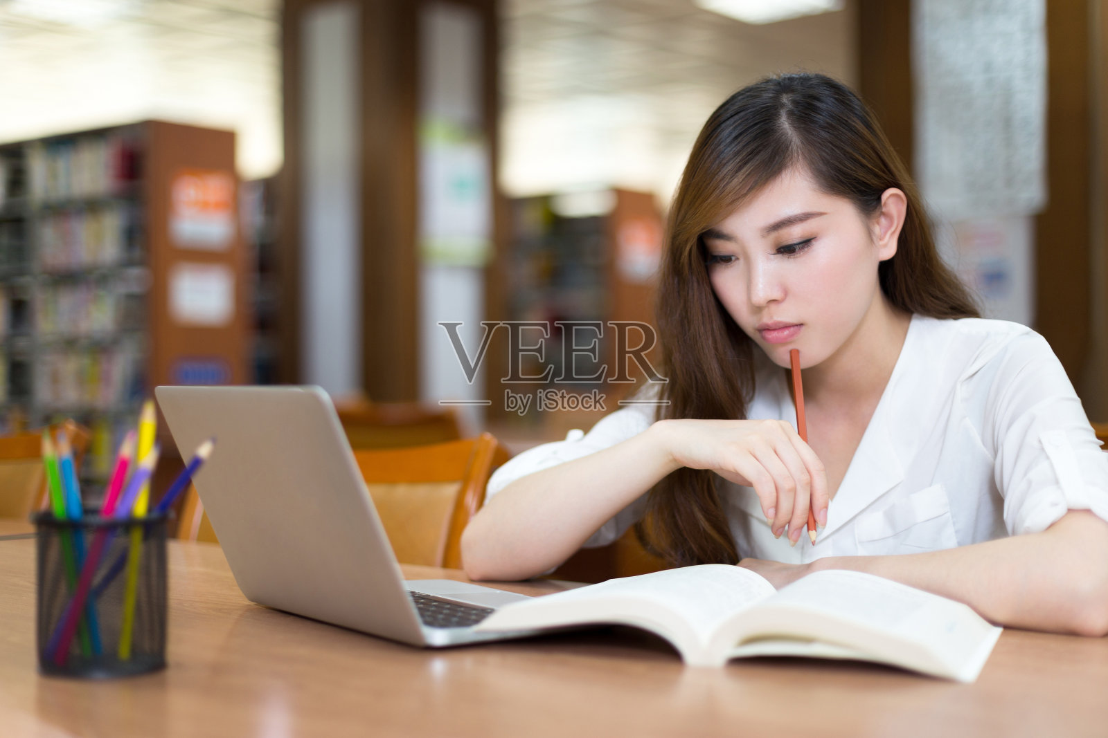 美丽的亚洲女学生使用笔记本电脑在图书馆学习照片摄影图片