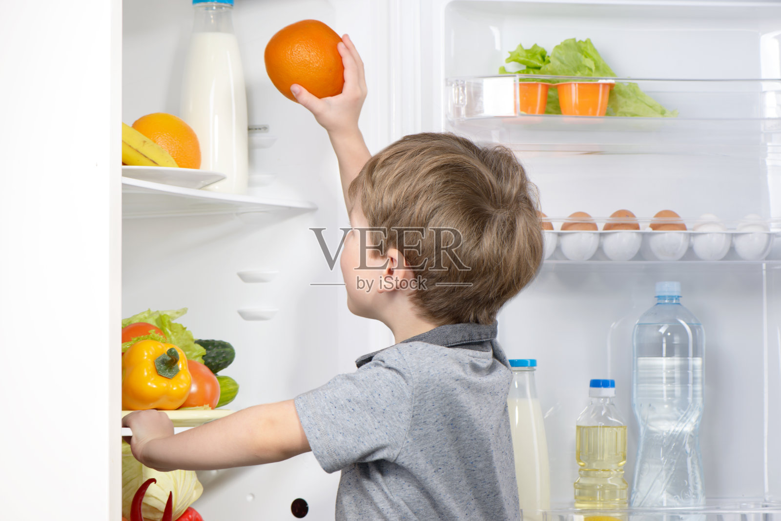 可爱的小男孩从冰箱里摘橘子照片摄影图片