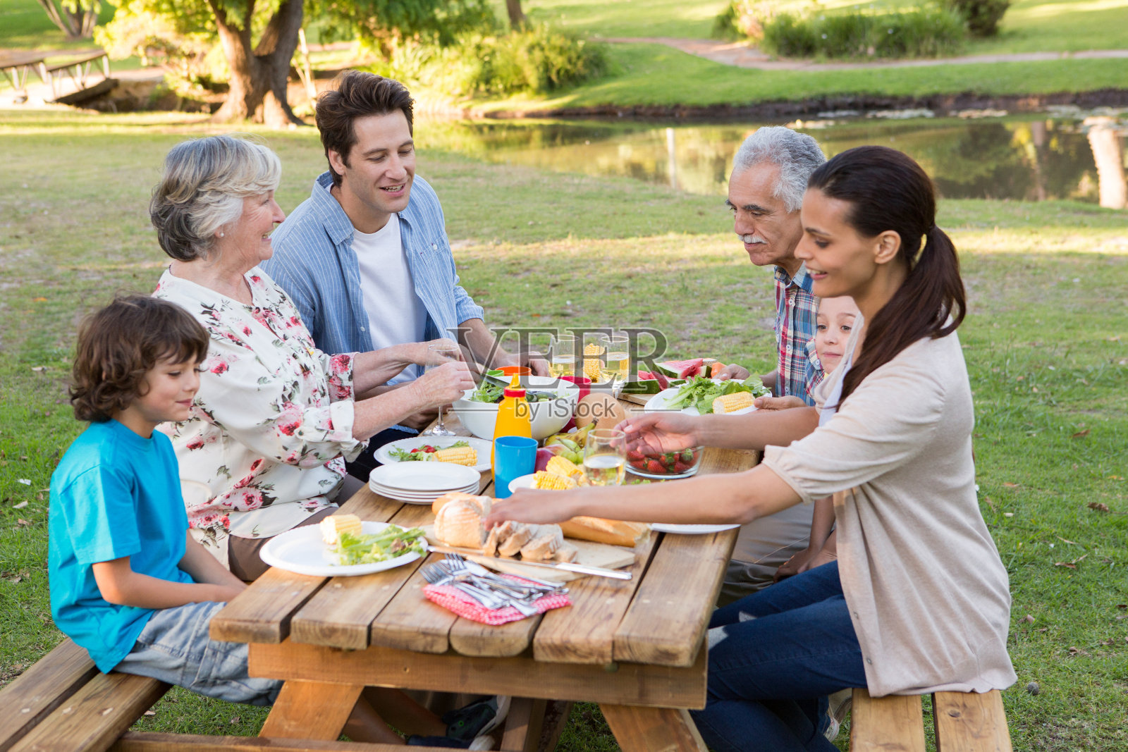 一个大家庭在外面的野餐桌上吃饭照片摄影图片