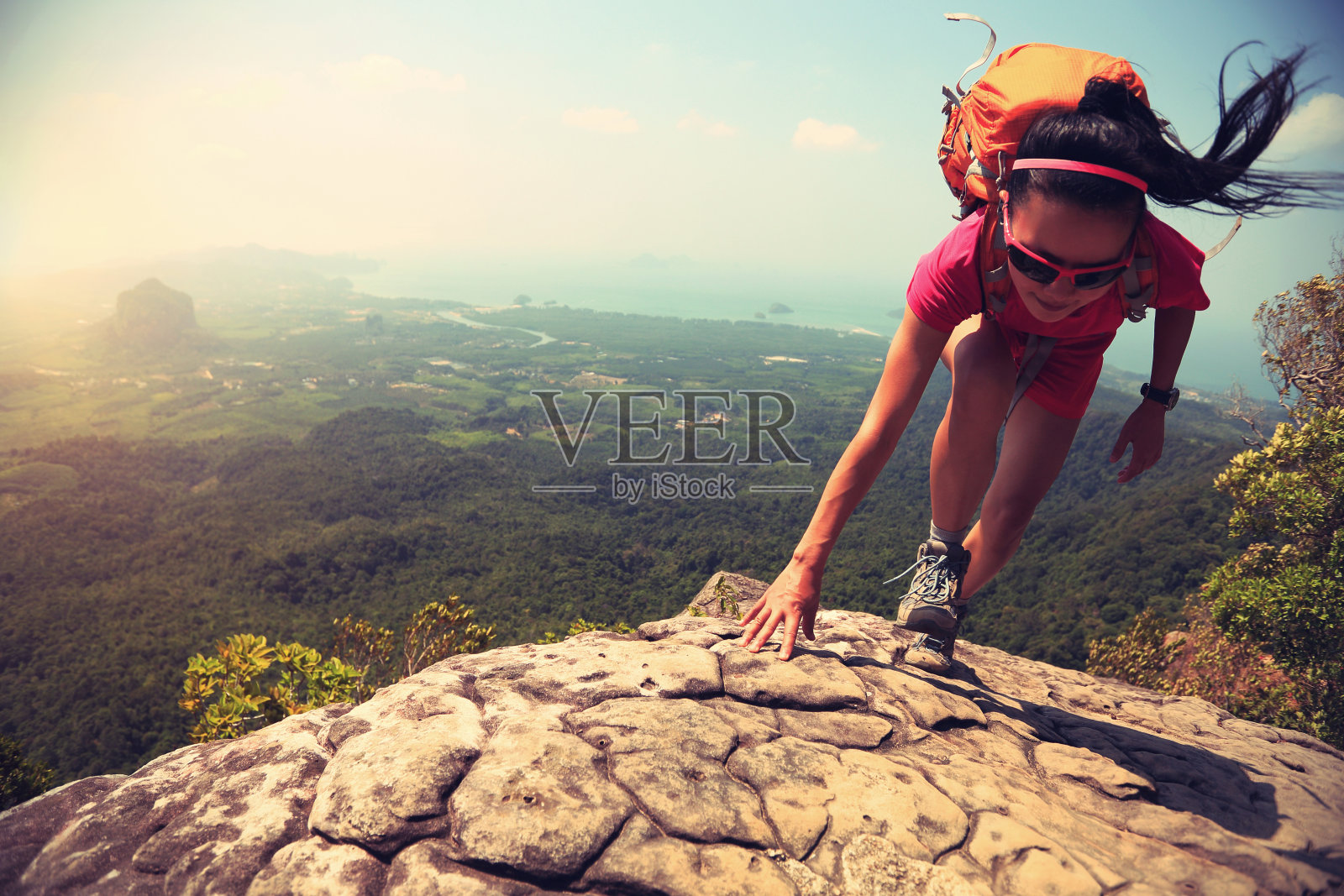 年轻的亚洲女子徒步旅行者攀登岩石的山峰悬崖照片摄影图片