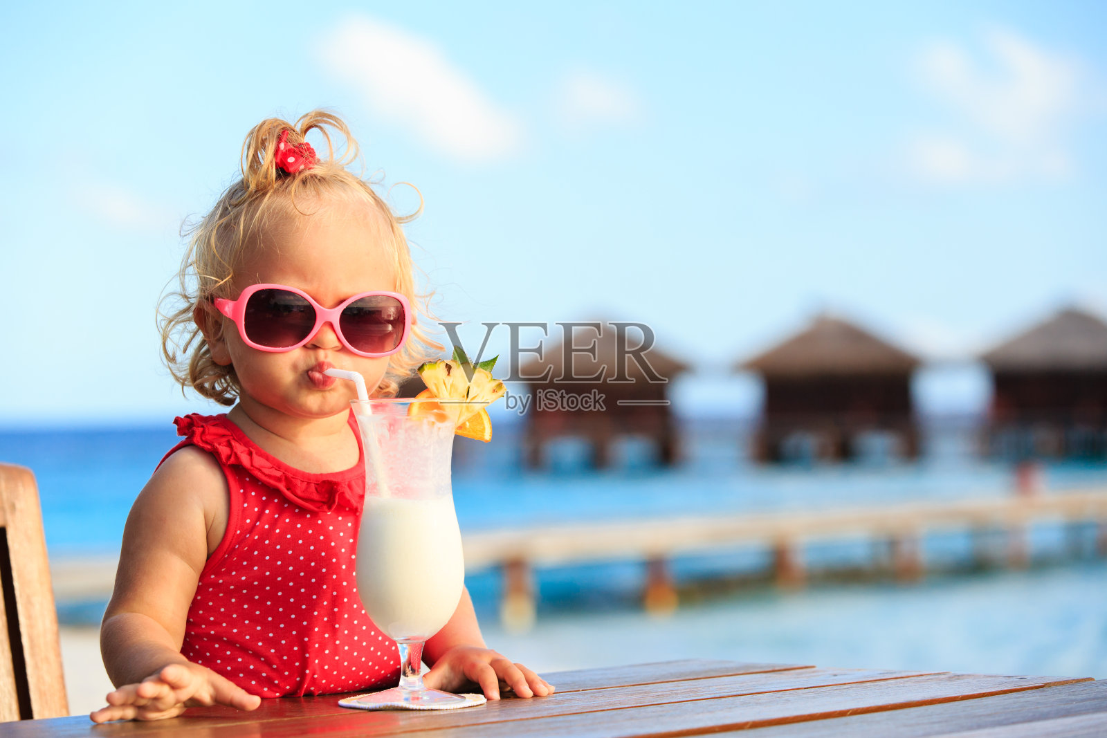 可爱的小女孩在热带海滩上喝鸡尾酒照片摄影图片