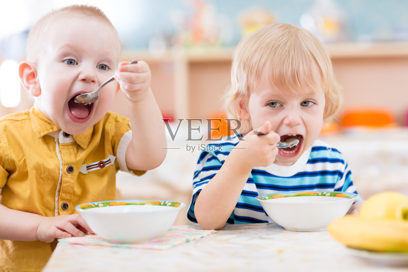 幼儿园里用盘子吃东西的有趣小孩照片摄影图片