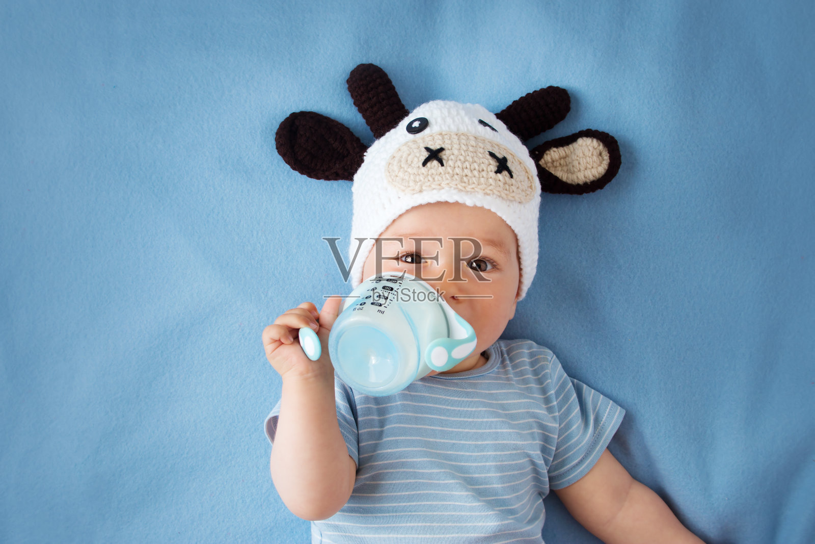 婴儿戴着牛帽喝牛奶照片摄影图片