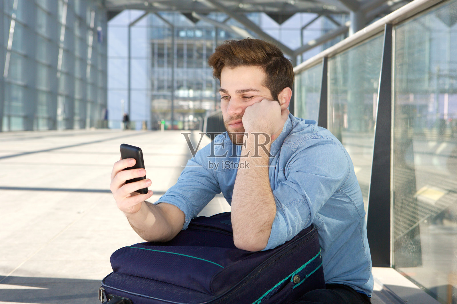 一名男子在机场候机，脸上带着无聊的表情照片摄影图片