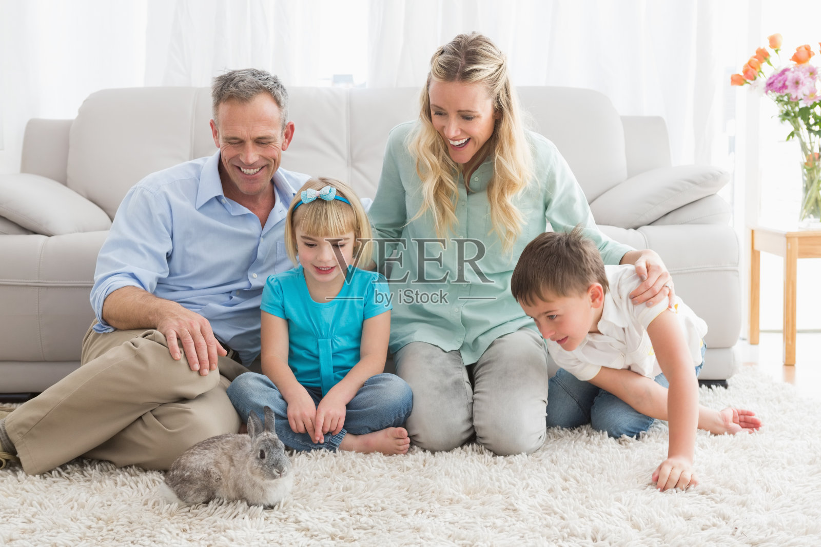 微笑的家庭和他们的兔子在地毯上照片摄影图片
