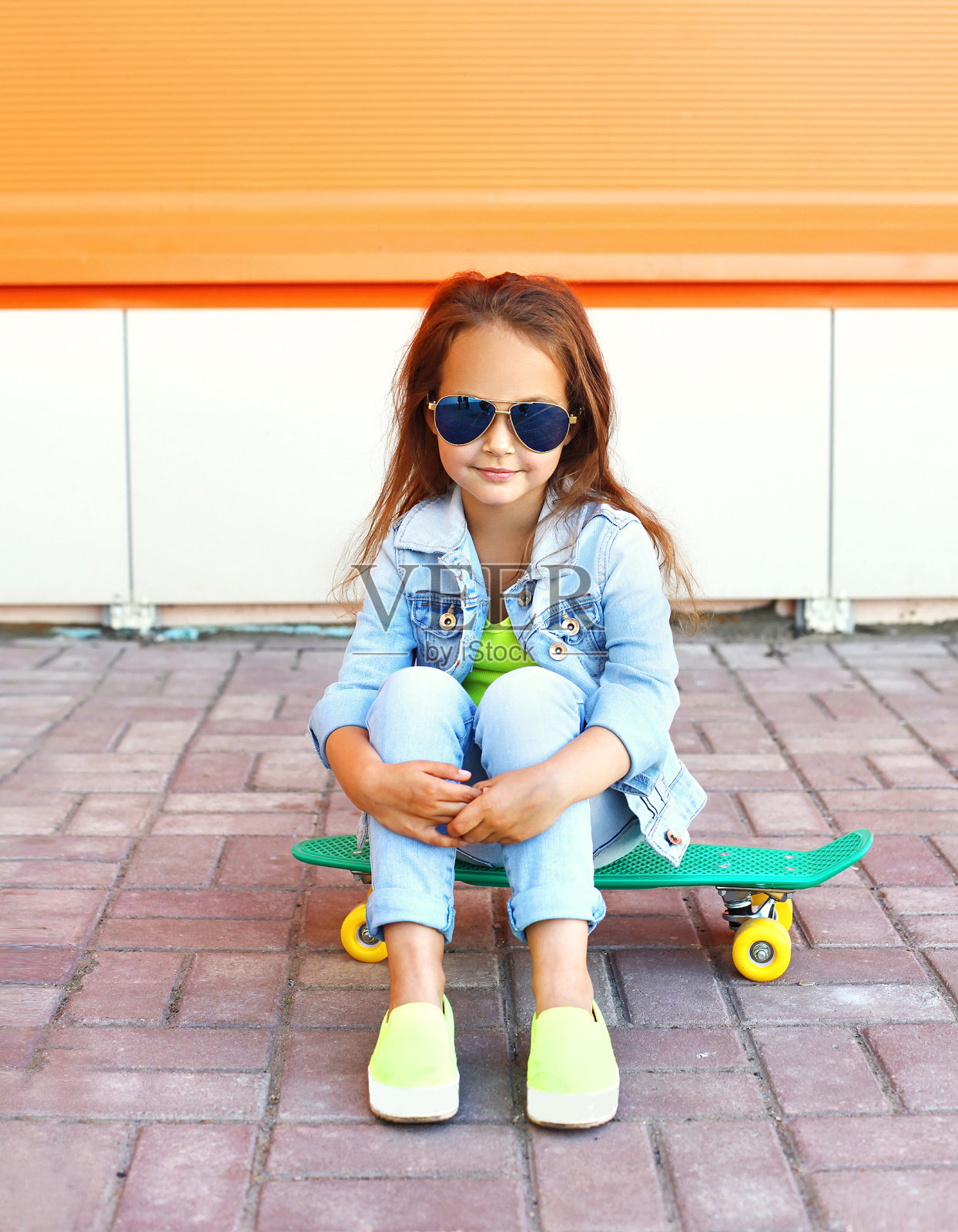 美丽的小女孩坐在滑板上在城市照片摄影图片