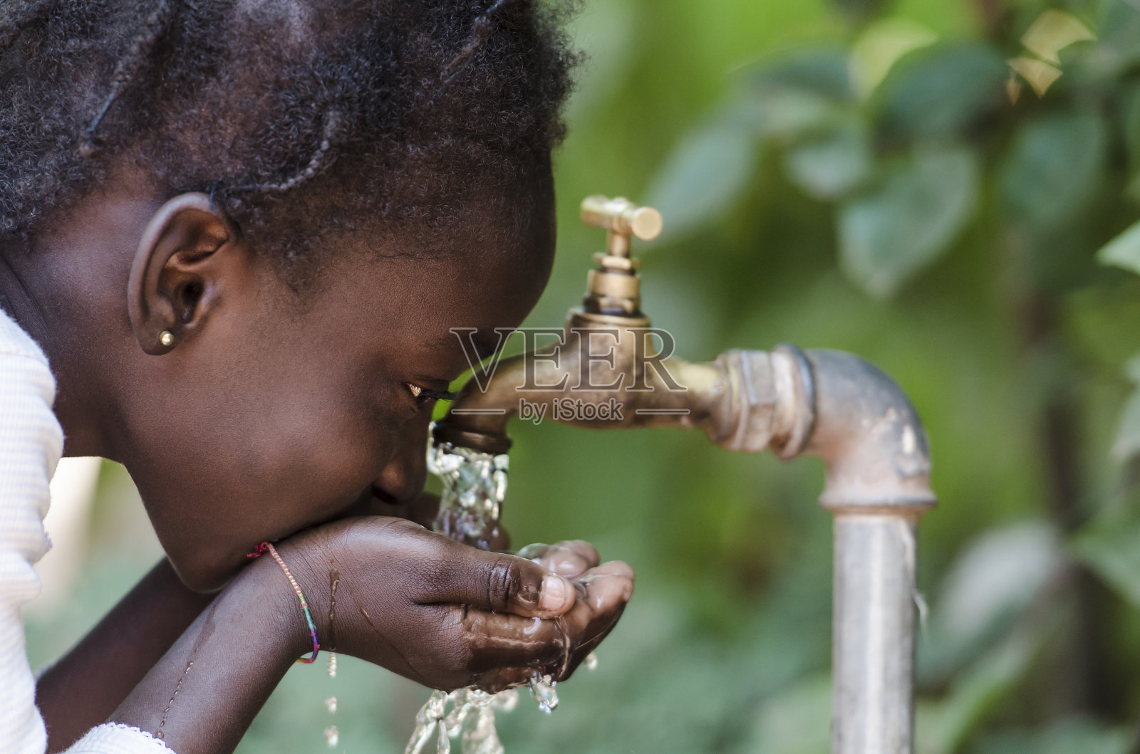 清洁淡水稀缺象征:黑人女孩从水龙头喝水照片摄影图片