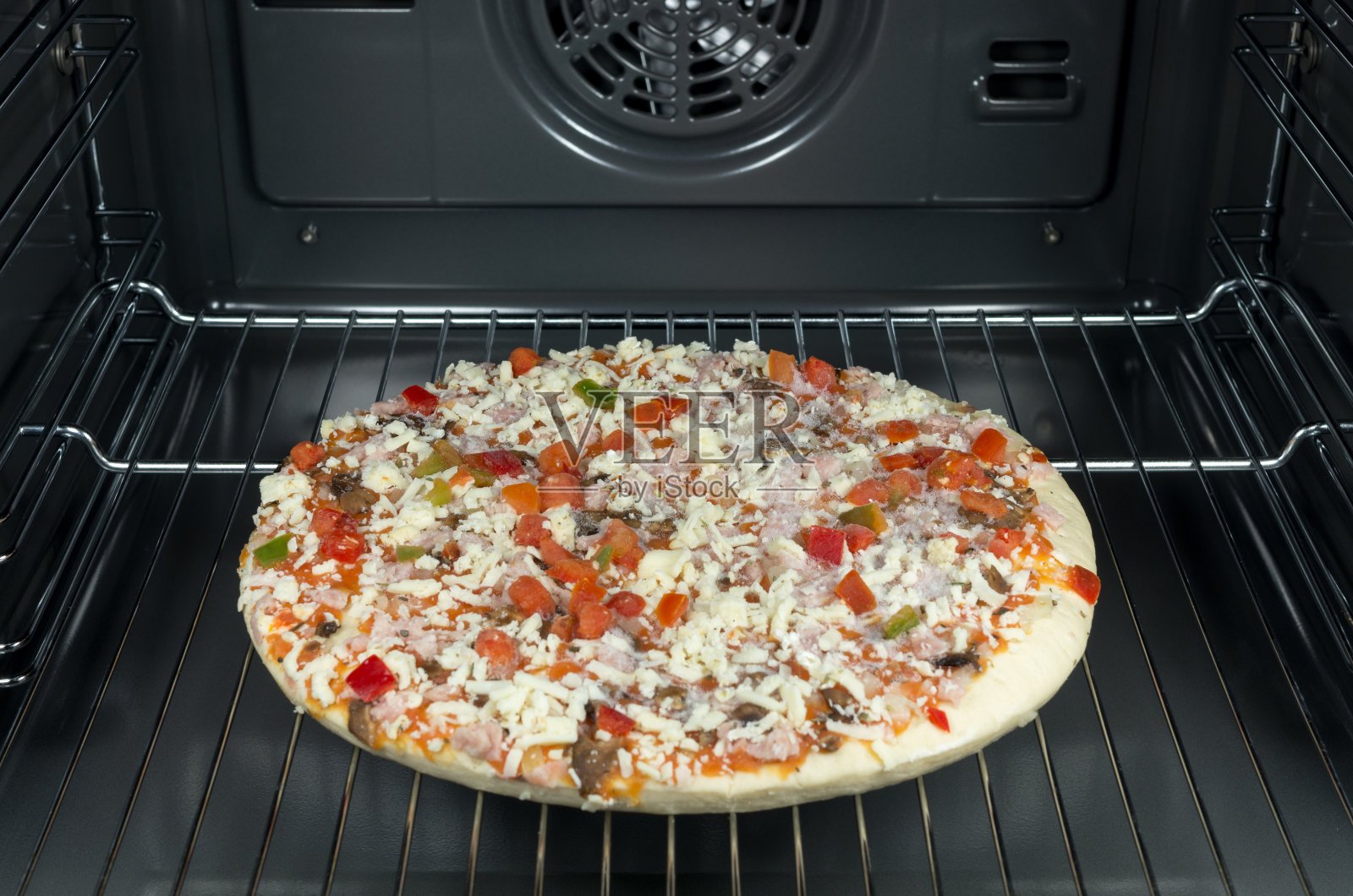 烤箱里的生披萨和冷冻披萨。照片摄影图片