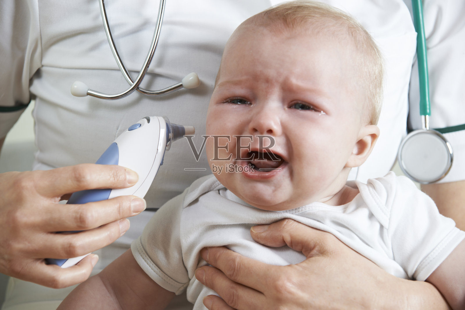 护士用数字体温计测量哭泣婴儿的体温照片摄影图片