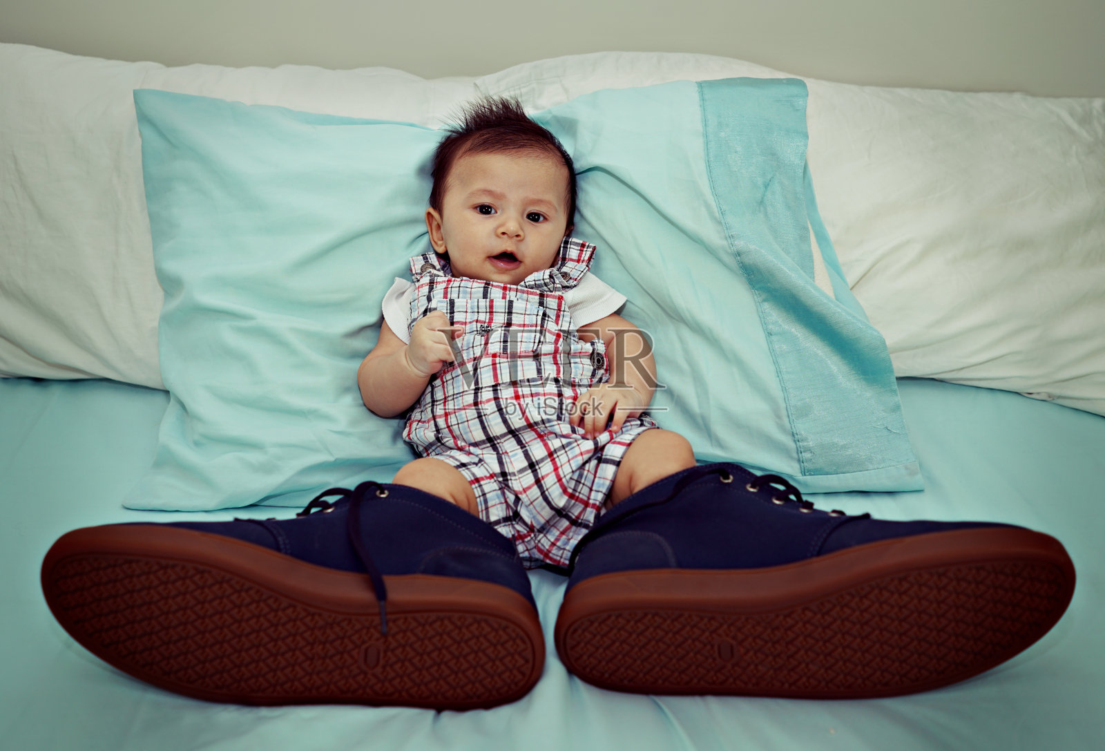 亚洲婴儿穿着大鞋在床上照片摄影图片