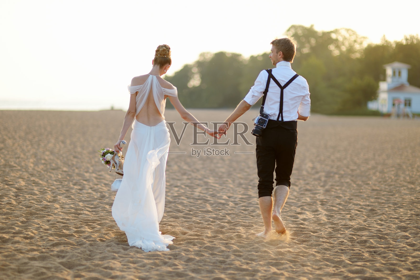 日落时分，新郎和新娘在海滩上照片摄影图片