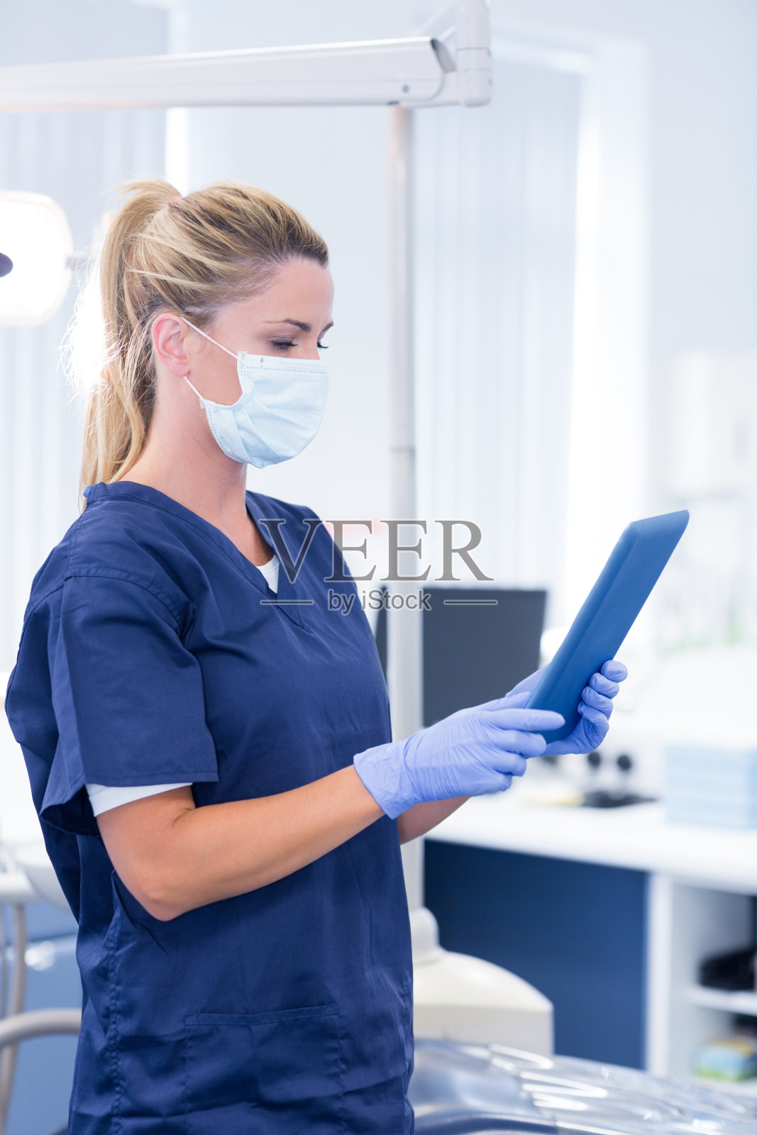 牙医戴着面具，用着她的药片照片摄影图片