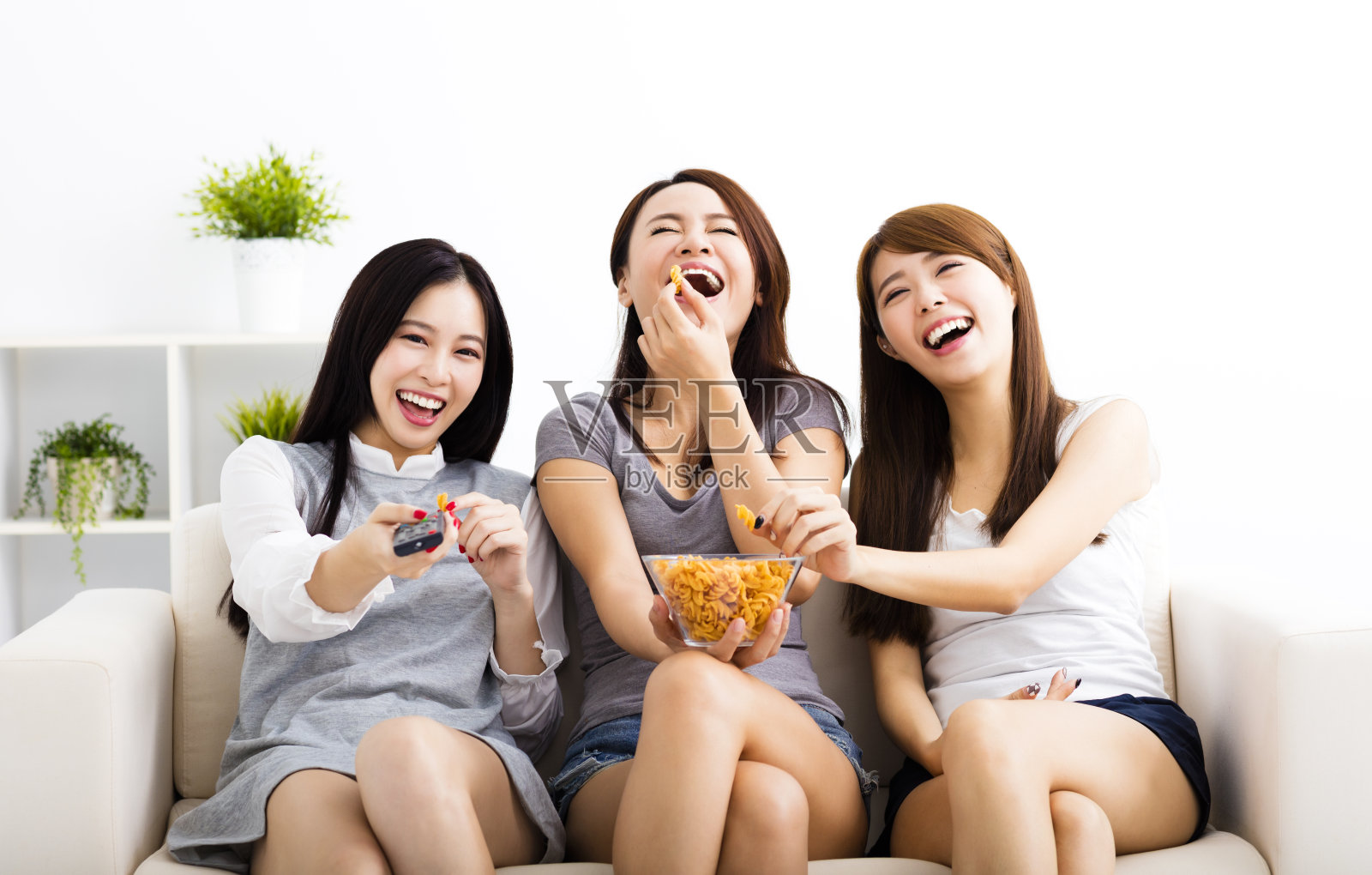 快乐的年轻女子群吃零食和看电视照片摄影图片