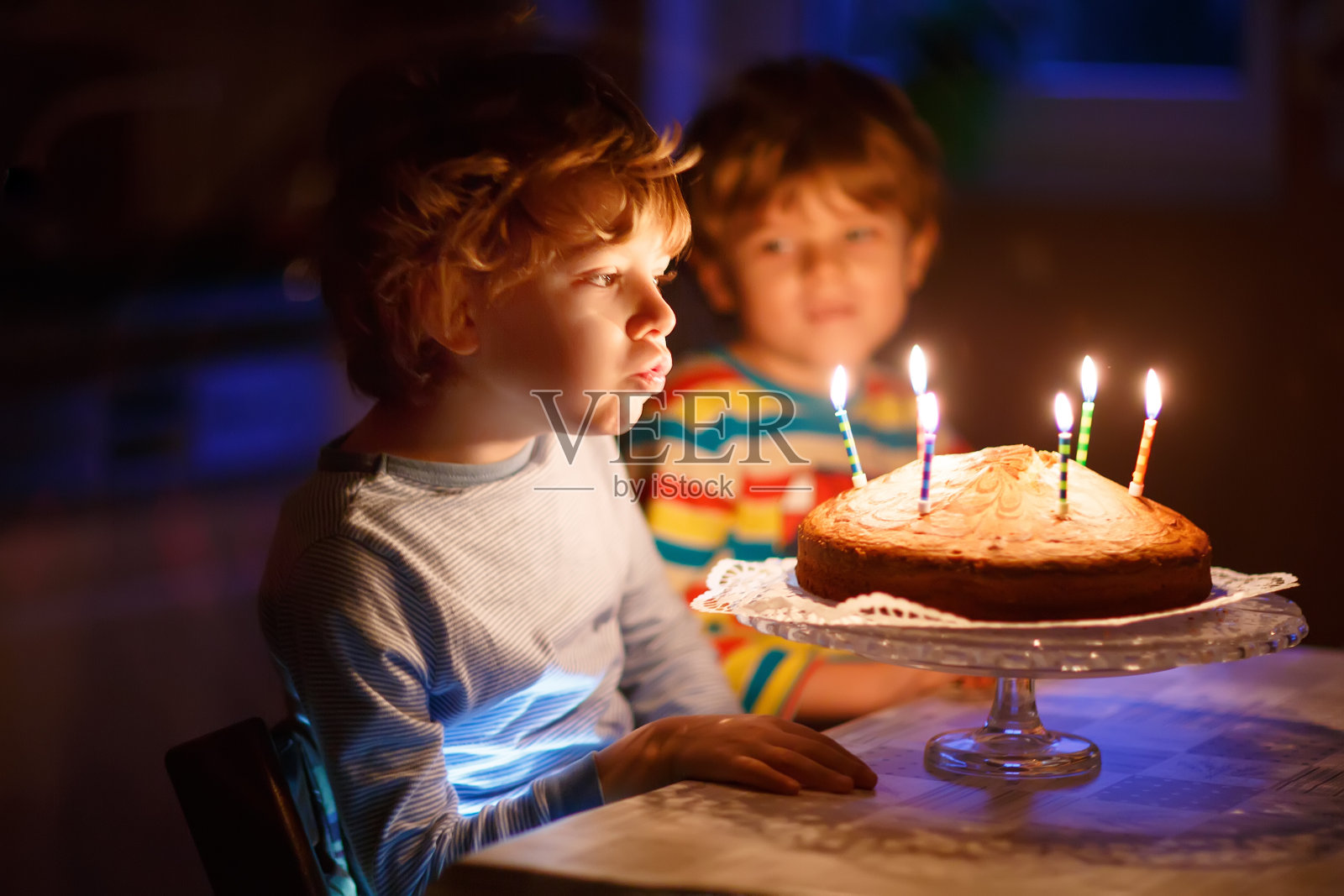 小男孩和哥哥在生日蛋糕上吹蜡烛照片摄影图片