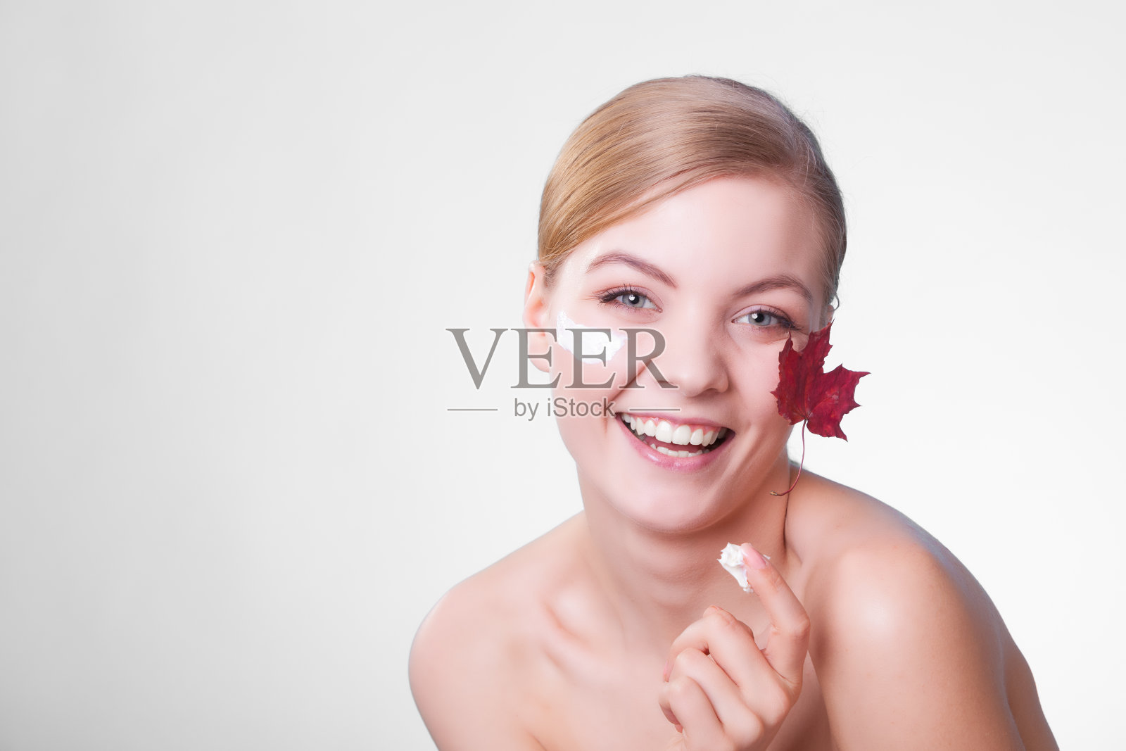 皮肤护理。年轻女子的脸上带着枫叶。照片摄影图片