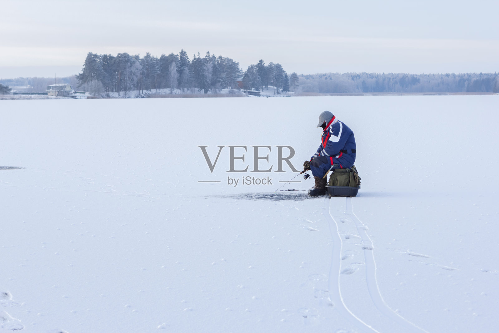 冰钓鱼。渔夫坐在结冰的湖面上钓鱼照片摄影图片
