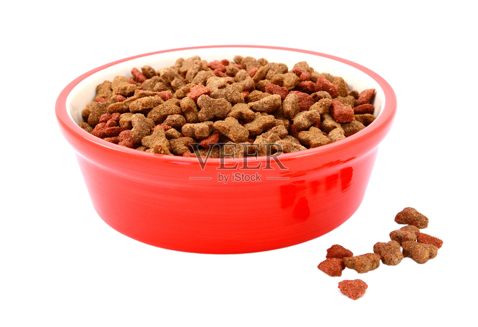 红色的碗里放着干猫粮，饼干洒在旁边照片摄影图片