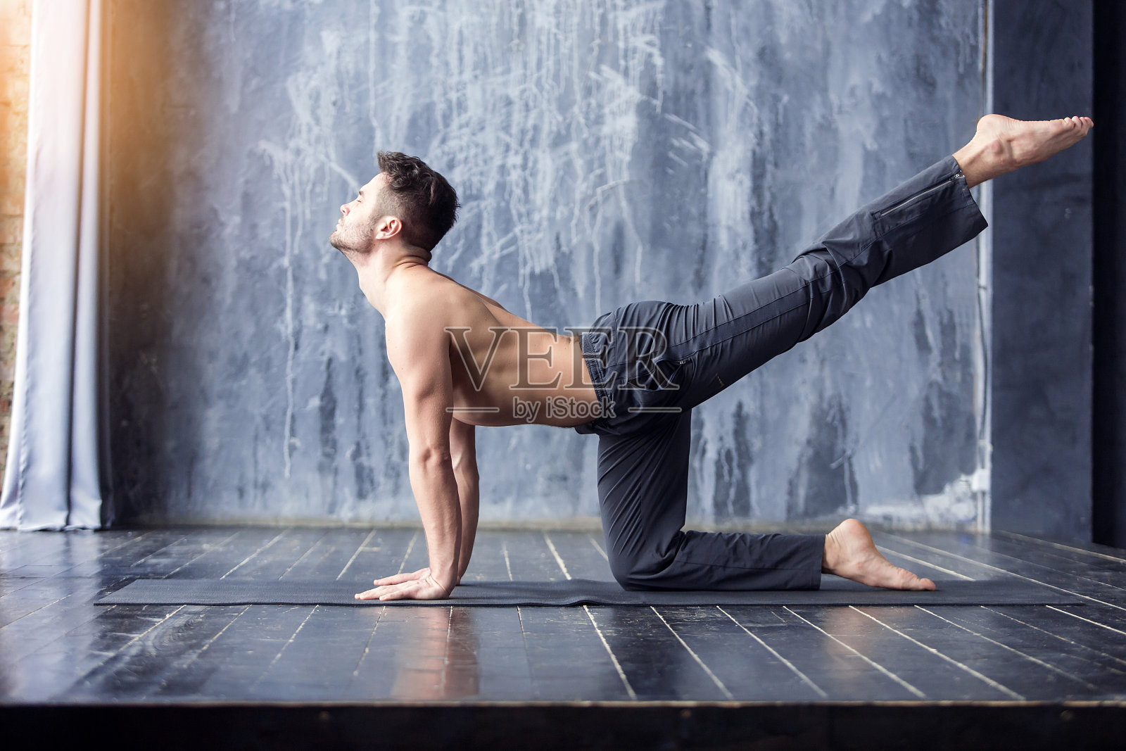 瑜伽男在黑色垫子上锻炼。照片摄影图片