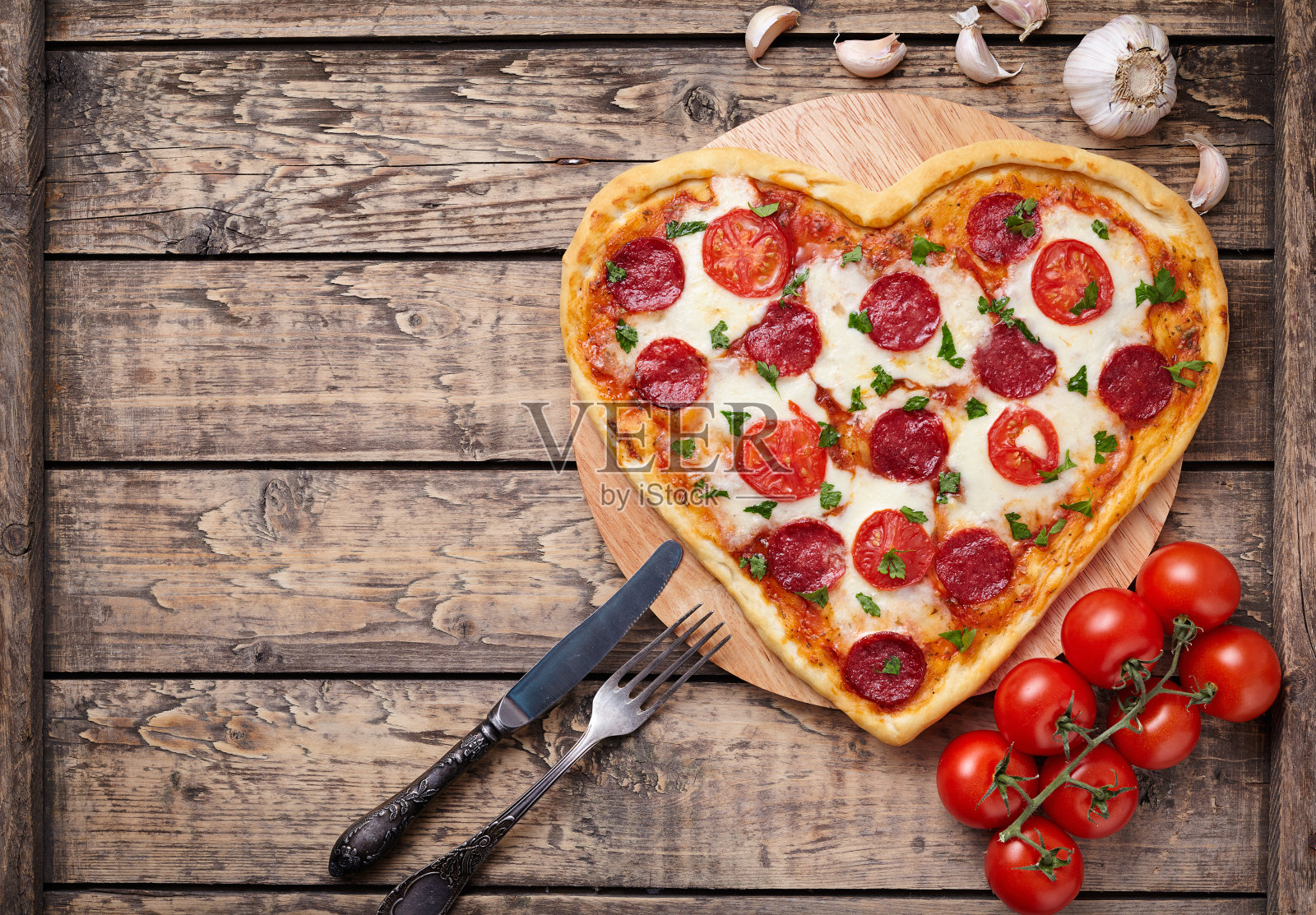 心形披萨，搭配意大利辣香肠、番茄和马苏里拉奶酪照片摄影图片