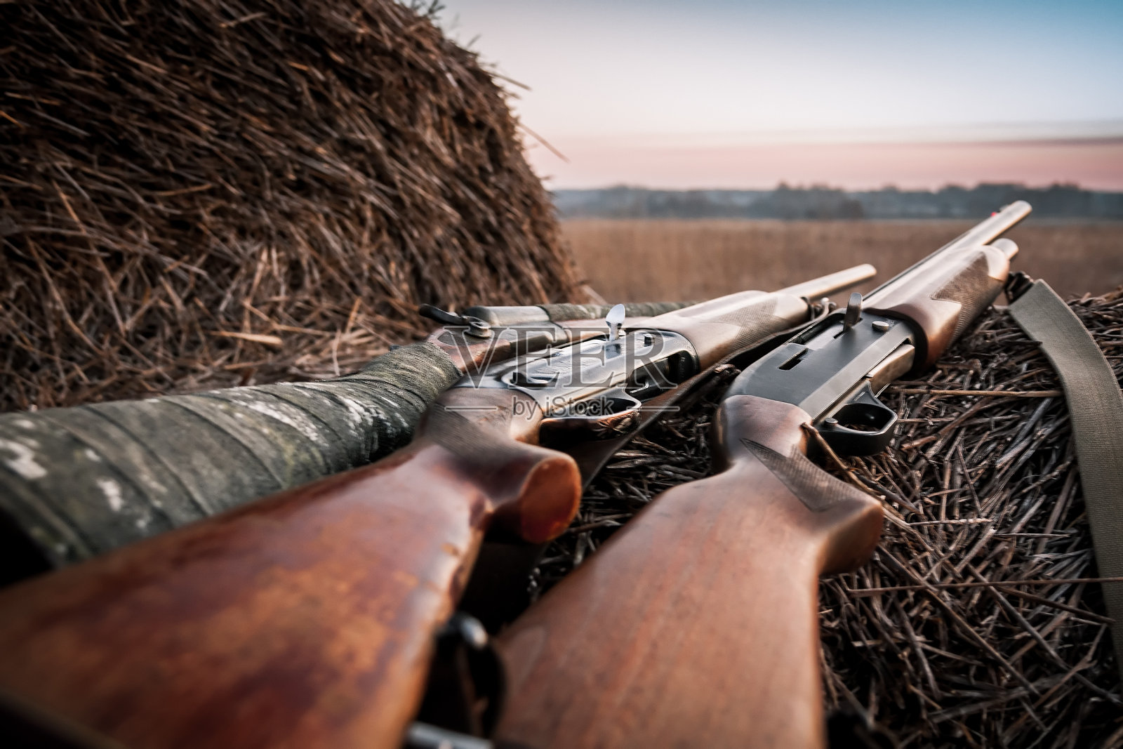 日出时在草堆上用猎枪狩猎照片摄影图片