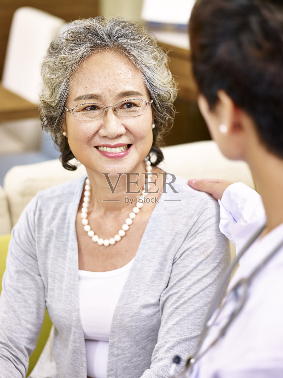 一位年长的亚洲女性正在和一位医务工作者交谈照片摄影图片