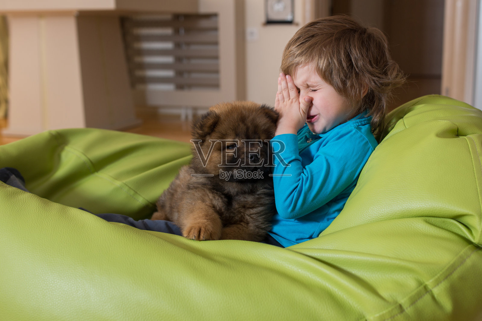 过敏的小男孩和小狗在豆袋上休息。照片摄影图片