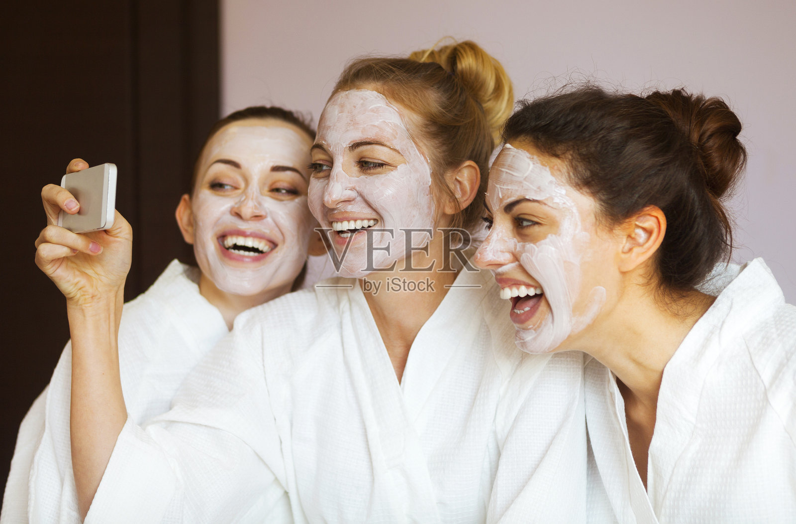三个年轻快乐的女人戴着面具在温泉度假村。照片摄影图片