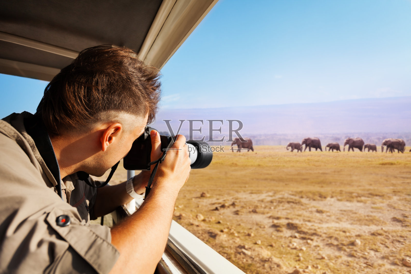 一名男子在非洲大草原拍摄大象照片摄影图片