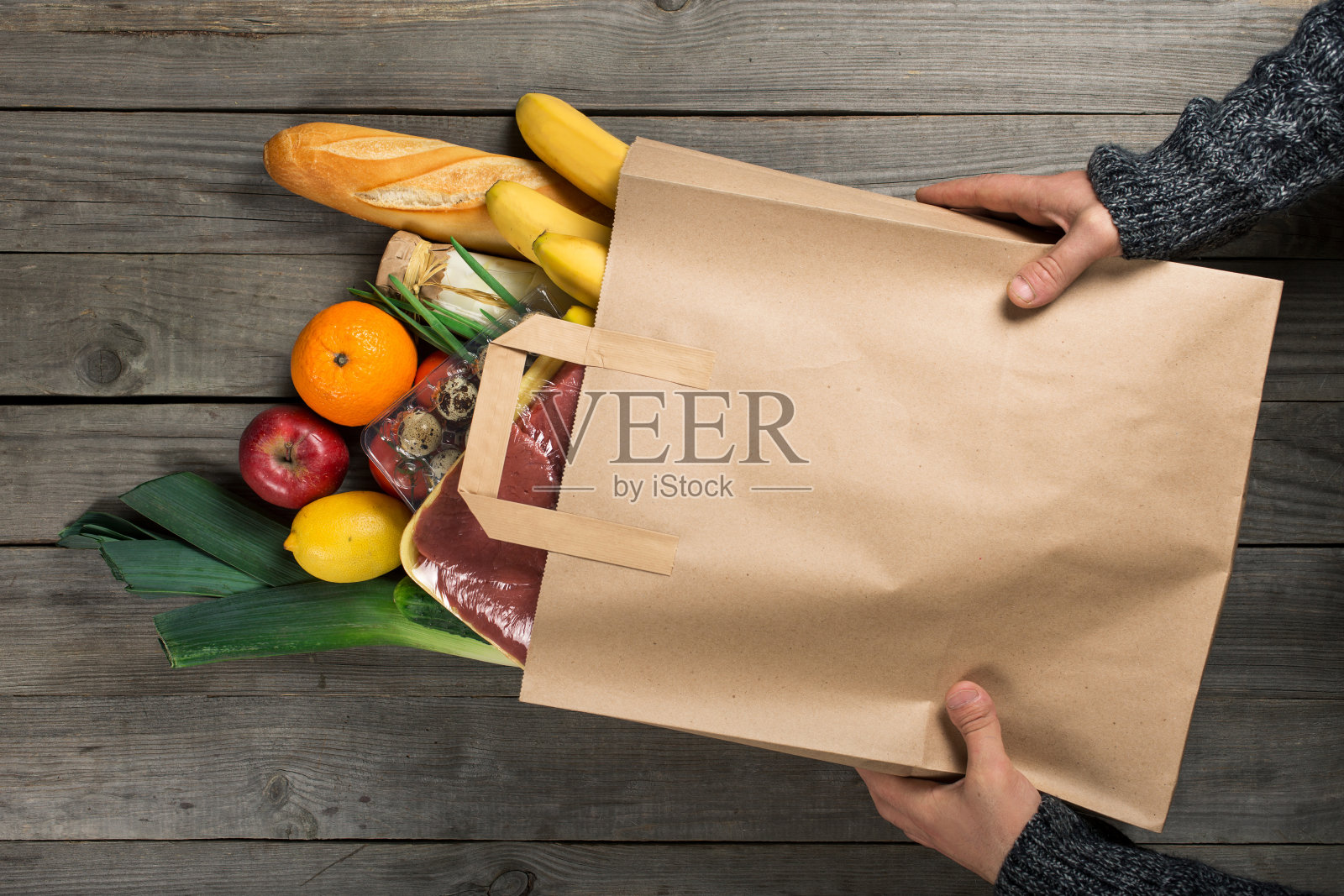 男人拿着袋子不同的健康食品在木制厨房照片摄影图片