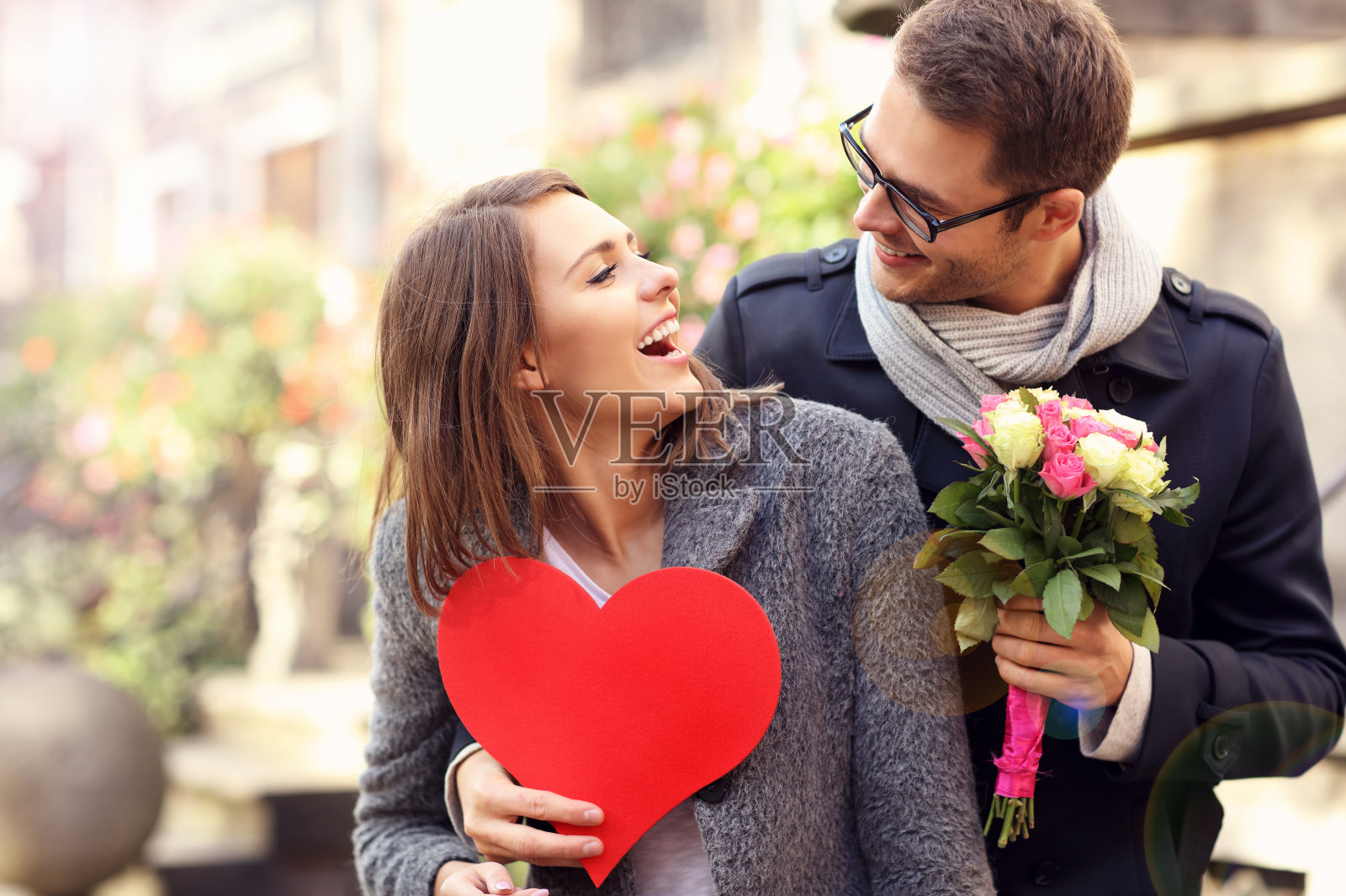 年轻的男人用鲜花和爱心给女人惊喜照片摄影图片