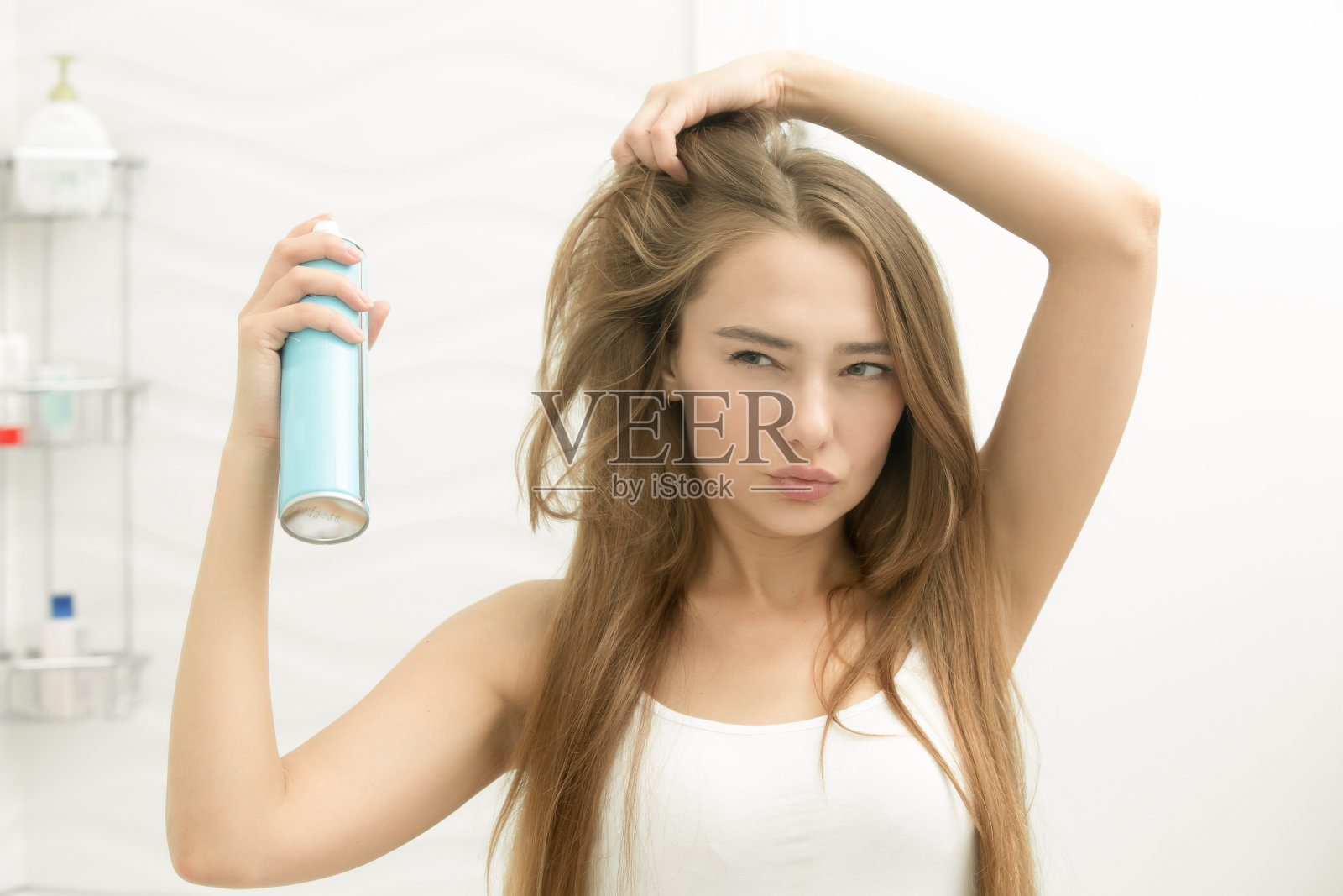 漂亮的年轻女孩正在往头发上喷发胶照片摄影图片