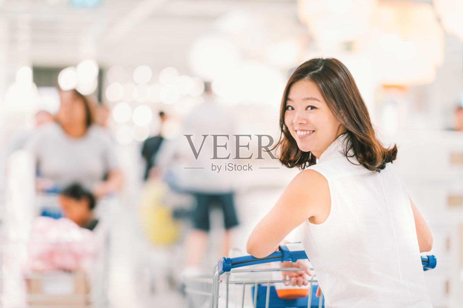 在购物中心推着购物车的亚洲妇女照片摄影图片