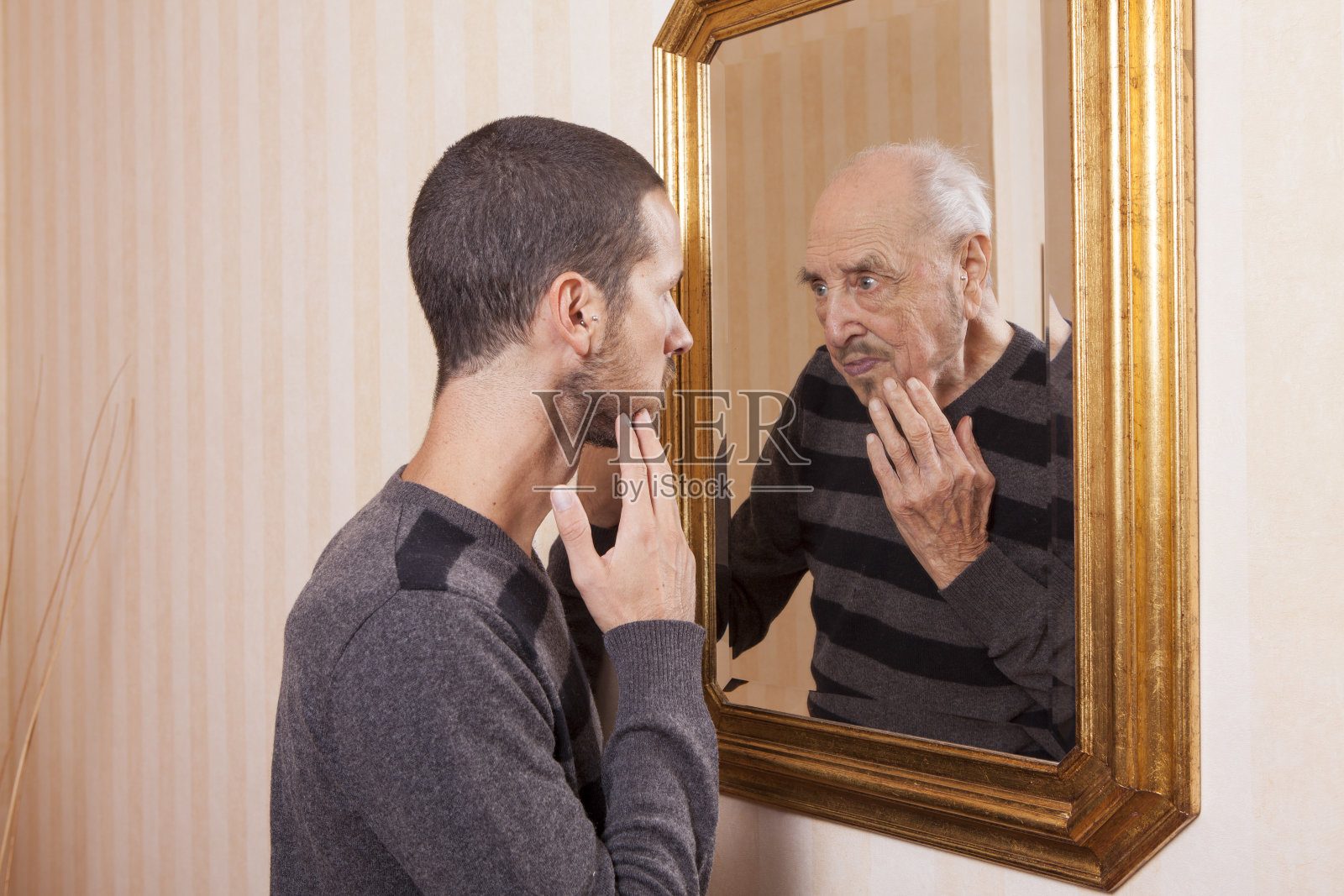 一个年轻人在镜子里看着一个变老的自己照片摄影图片