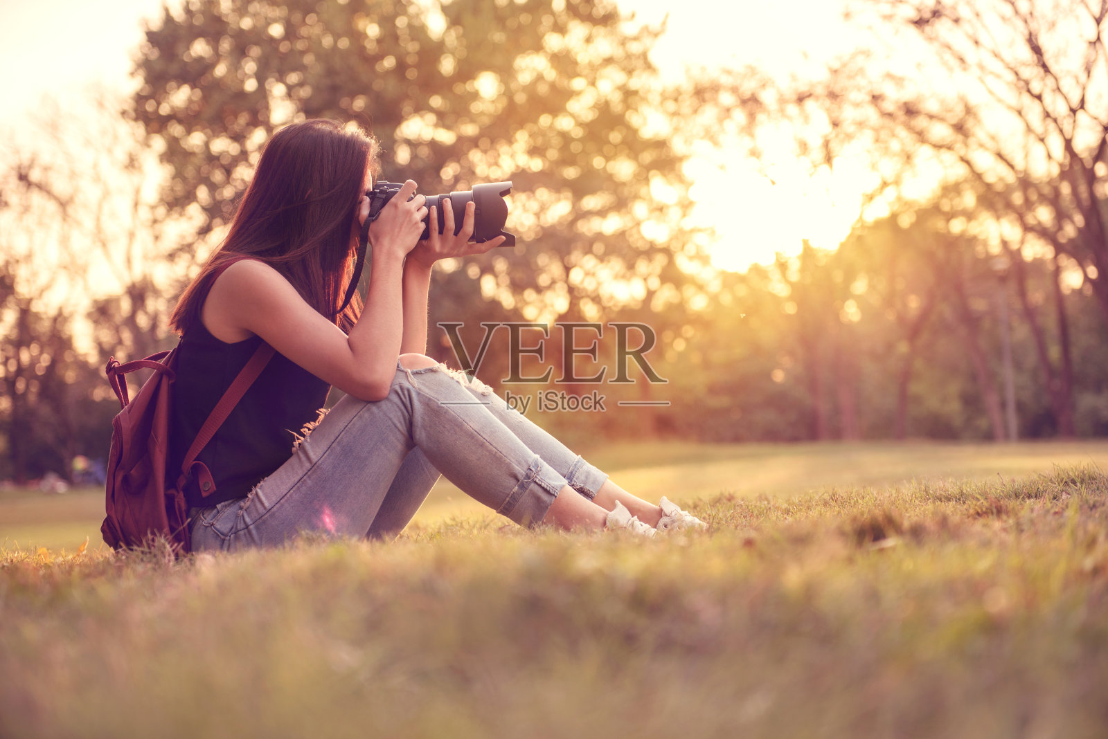 女人是一个带着单反相机的摄影师，户外和阳光。照片摄影图片
