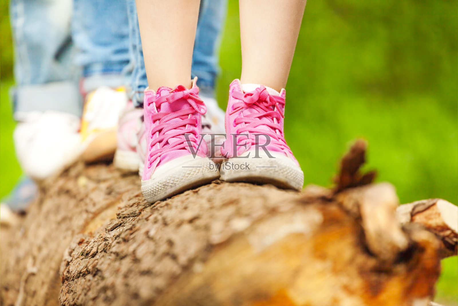 孩子们穿着粉色运动鞋站在一根木头上照片摄影图片